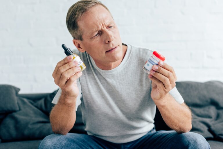 handsome man in t-shirt holding medical cannabis and cannabis oil